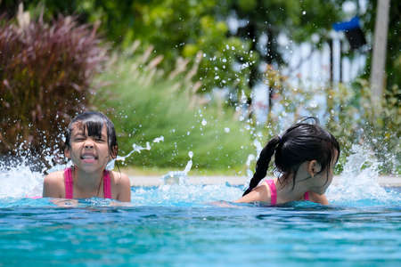 Two cute little girls playing in the pool. Summer lifestyle concept.の写真素材