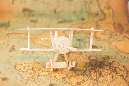 Wooden toy plane on world map on table. Travel and vacation concepts.の写真素材