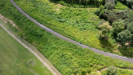Aerial view of a drone on a railway track in a rural landscape with green forest during the rainy season. The drone flew above the forest and saw the railroad tracks in the distance.の写真素材