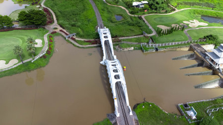 Aerial view of Tha Chomphu White Bridge, Lamphun, Thailand with river, forest trees and green...