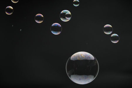 Flying soap bubbles on black background. Abstract soap bubbles with colorful reflections. Soap bubbles in motion background.の写真素材