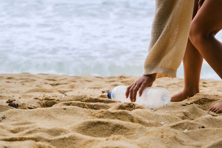 Woman cleaning plastic on the beach. People voluntarily clean nature from plastic. Concept of plastic pollution and environmental problemsの写真素材