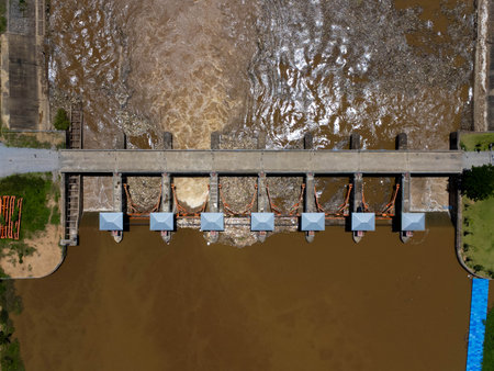 Aerial view of the water released from the concrete dam's drainage channel as the overflow in the rainy season. Top view of turbid brown forest water flows from a dam in rural northern Thailand.の写真素材