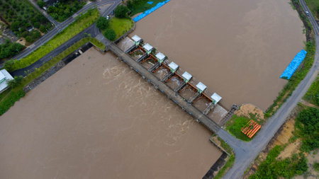 Aerial view of the water released from the concrete dam's drainage channel as the overflow in the rainy season. Top view of turbid brown forest water flows from a dam in rural northern Thailand.の写真素材