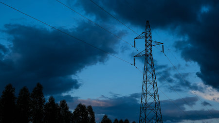 Electric poles and wires in the blue sky with clouds in the countryside.