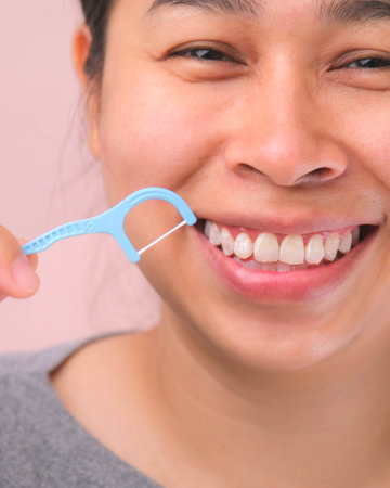Close-up of smiling asian woman and cleaning for perfect smile. Healthy white teeth by flossing, oral health and dental care.の写真素材