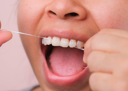 Close-up of smiling asian woman and cleaning for perfect smile. Healthy white teeth by flossing, oral health and dental care.の写真素材