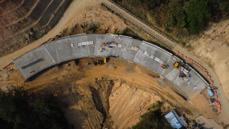Aerial view of development of new road construction or overpass under construction. Top view from a drone above road construction workers among the mountains.の写真素材