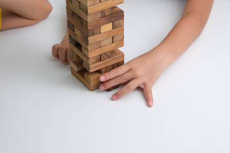 Cute Asian siblings having fun playing together. Two children playing board game on table in room at home. Wooden puzzles are games that increase intelligence for children. Educational toys for children.の写真素材