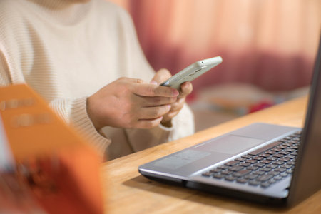 Young Asian woman using smartphone and working sitting in office at home close-up.の写真素材