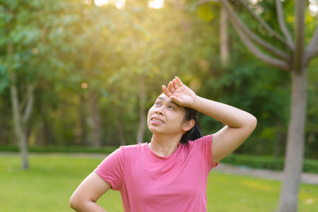 Portrait of young Asian woman in sportswear resting after jogging. Healthy young woman taking a break after jogging in the park. Healthy lifestyle concept.の写真素材