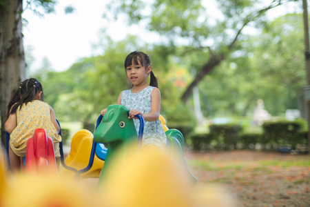 Happy girl having fun on a carousel. Children playing at outdoor playground in the park on summer vacation. Healthy activity.の写真素材