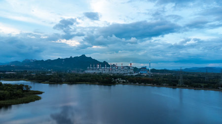 Coal-fired power plant with lake on green mountain background and blue sky. Mae Moh coal power plant in Lampang, Thailand.の写真素材