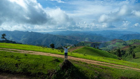Tourists stand on the rocks enjoying the picturesque hillside views with vast fields on a beautiful sunny day with blue sky and clouds in springtime.の写真素材
