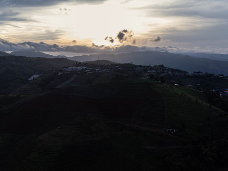 Aerial view of beautiful sunrise or sunset sky and rural villages. Village landscape in misty valley and mountain clouds in thailand.の写真素材