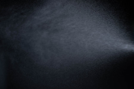 Water spray dust on dark background. Spraying mist effect isolated on black background.の写真素材
