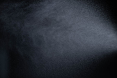 Water spray dust on dark background. Spraying mist effect isolated on black background.の写真素材
