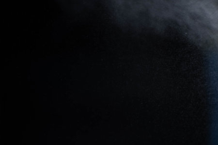 Water spray dust on dark background. Spraying mist effect isolated on black background.の写真素材