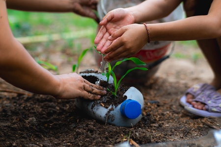 Little girl and mom grow plants in pots from recycled water bottles in the backyard. Recycle water bottle pot, gardening activities for children. Recycling of plastic wasteの写真素材