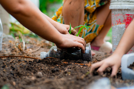 Little girl and mom grow plants in pots from recycled water bottles in the backyard. Recycle water bottle pot, gardening activities for children. Recycling of plastic wasteの写真素材