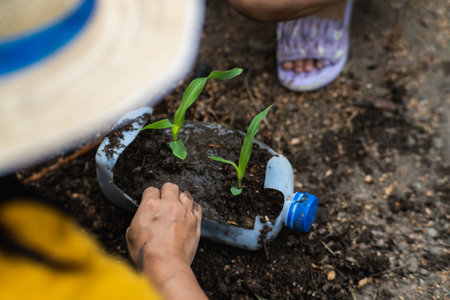 Little girl and mom grow plants in pots from recycled water bottles in the backyard. Recycle water bottle pot, gardening activities for children. Recycling of plastic wasteの写真素材