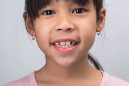 Close-up of cute young girl smiling wide, showing empty space with growing first front teeth. Little girl with big smile and missing milk teeth. Dental hygiene conceptの写真素材