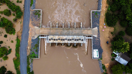 Aerial view of water released from the drainage channel of the concrete dam is a way of overflowing water in the rainy season. Top view of turbid brown forest water flows from a dam in Thailand.の写真素材