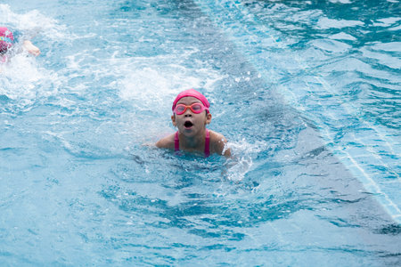 Pretty little girl swimming and playing in water. Children in swimming pool having fun during family summer vacation.の写真素材