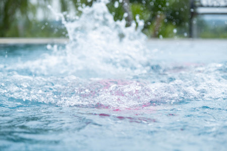 Child jumping in swimming pool, water splashing. Children in swimming pool having fun during family summer vacation.の写真素材