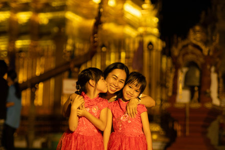 Happy family, mother and her children pose for the camera at Golden pagoda at Wat Phra That Haripunchai Woramahawihan in Lamphun, north of Thailand.の写真素材