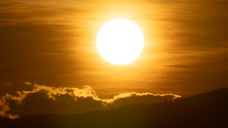 Closeup of bright big sun on the sky with orange gradient colors in a calmly evening.の写真素材