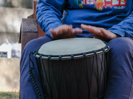 Asian man playing rhythmic instrument. A man plays a long drum at a party. Thai musical instrumentsの写真素材