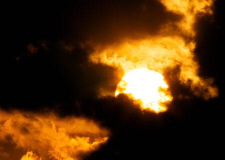 Beautiful nature sky with orange, yellow sunshine and fluffy clouds. Time lapse of a beautiful dramatic sky with a big sun at sunset or sunrise.の写真素材