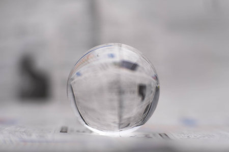 A glass globe reveals the letters inside, with a newspaper in the background.の写真素材
