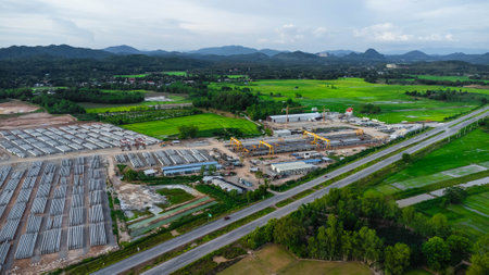 Aerial view of a new road development or highway under construction. Top view from a drone over road construction workers amidst mountains. Construction Site with Cranes and Heavy Equipment.の写真素材