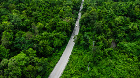 Aerial view of countryside asphalt road with car and green forest. Drive on the road between green forests.の写真素材