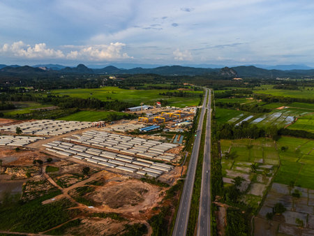 Aerial view of a new road development or highway under construction. Top view from a drone over road construction workers amidst mountains. Construction Site with Cranes and Heavy Equipment.の写真素材