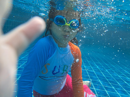 Girl taking a photo of herself underwater happilyGirl taking a photo of herself underwater happilyの写真素材