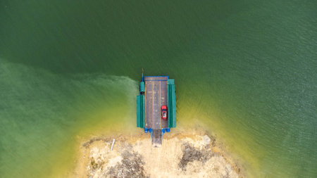 Aerial view of local ferry transporting cars, motorcycles and people across a river in Kanchanaburi Province, Thailand.の写真素材