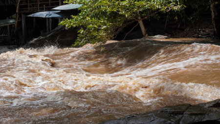 A strong current near a waterfall. Floods flowing in mountain rivers after heavy rains. Flash floods, the effects of global warming and the effects of deforestation.の写真素材