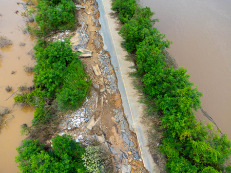 Landslides caused by heavy rains have caused the asphalt roads to crack. Natural disasters from flooding have damaged and cut off the road surface along the river.の写真素材