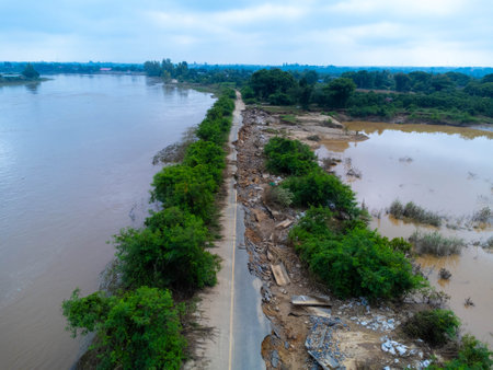 Landslides caused by heavy rains have caused the asphalt roads to crack. Natural disasters from flooding have damaged and cut off the road surface along the river.の写真素材