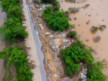 Landslides caused by heavy rains have caused the asphalt roads to crack. Natural disasters from flooding have damaged and cut off the road surface along the river.の写真素材