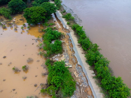 Landslides caused by heavy rains have caused the asphalt roads to crack. Natural disasters from flooding have damaged and cut off the road surface along the river.の写真素材