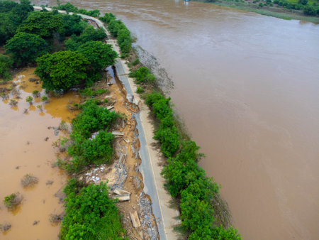 Landslides caused by heavy rains have caused the asphalt roads to crack. Natural disasters from flooding have damaged and cut off the road surface along the river.の写真素材