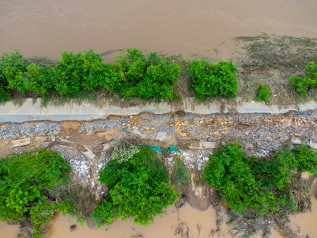 Landslides caused by heavy rains have caused the asphalt roads to crack. Natural disasters from flooding have damaged and cut off the road surface along the river.の写真素材