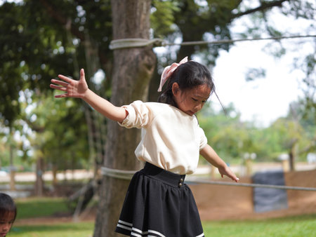 Cute little girl walking on balance beam in outdoor park. Children playing in the playground during summer vacation.の写真素材