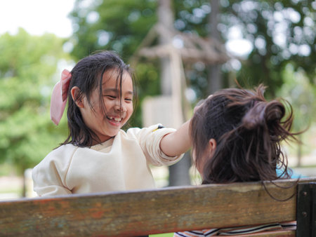 A younger sister comforts her older sister who is sitting sadly on a park bench.の写真素材