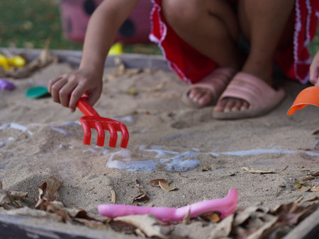 A cute little girl is learning about excavating a simulated dinosaur fossil in a playground.の写真素材