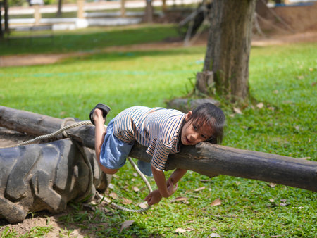 Cute little girl walking on balance beam in outdoor park. Children playing in the playground during summer vacation.の写真素材